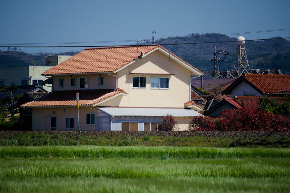 緑と丘に囲まれた赤い瓦屋根の家が特徴的な静かな田園風景。