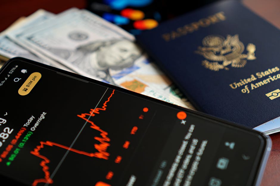 旅行と金融を象徴する株価チャート、現金、米国のパスポートが入ったスマートフォンのクローズアップ。