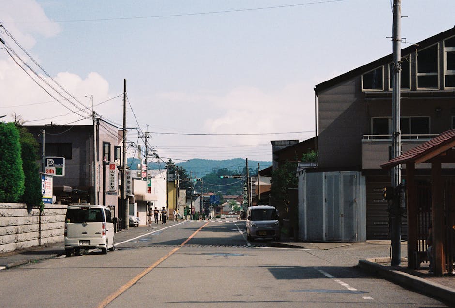 日本の山梨県にある、山々を背景に地元の建築物が並ぶ趣のある通り。