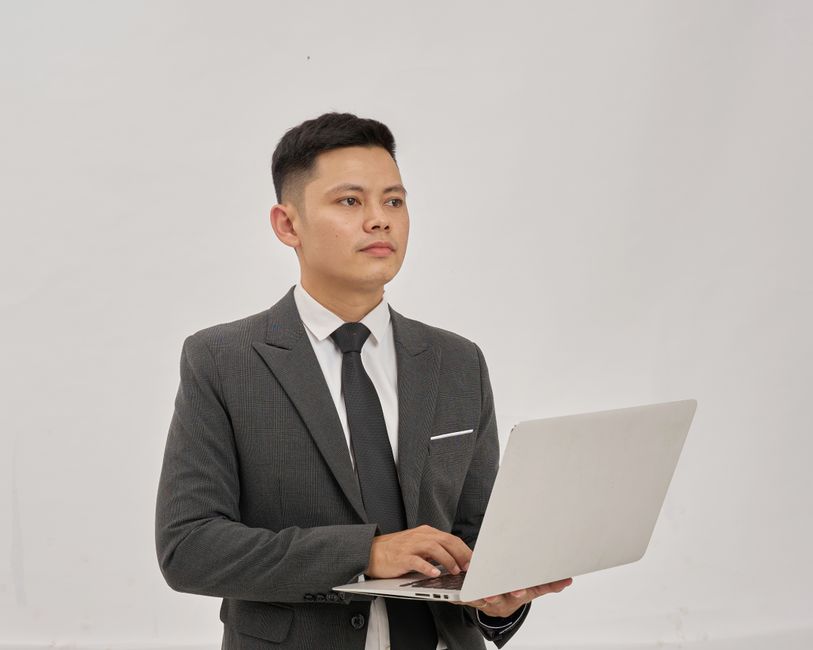 明るい屋内環境でノートパソコンを使用するスーツを着た自信に満ちたビジネスプロフェッショナル。