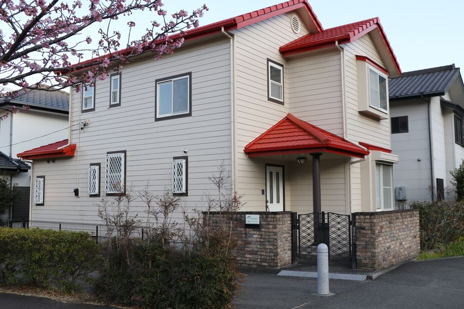 鮮やかな赤い屋根が、満開の桜に囲まれた、モダンな郊外住宅。