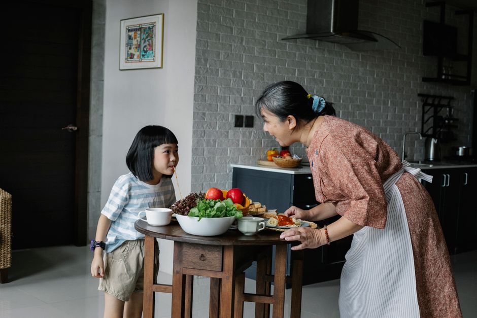 健康的な昼食を準備している小さな女の子と幸せな女性