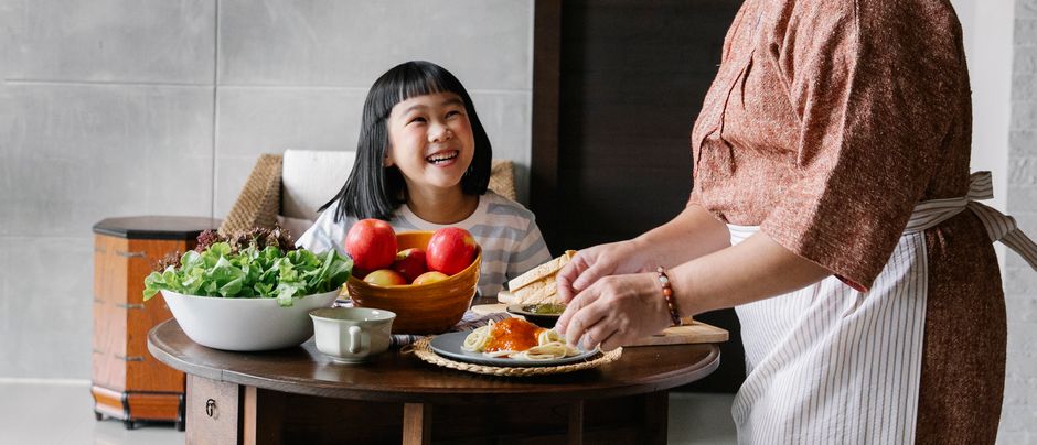 うれしそうなアジアの女の子とおばあちゃんが昼食のためにテーブルに集まります